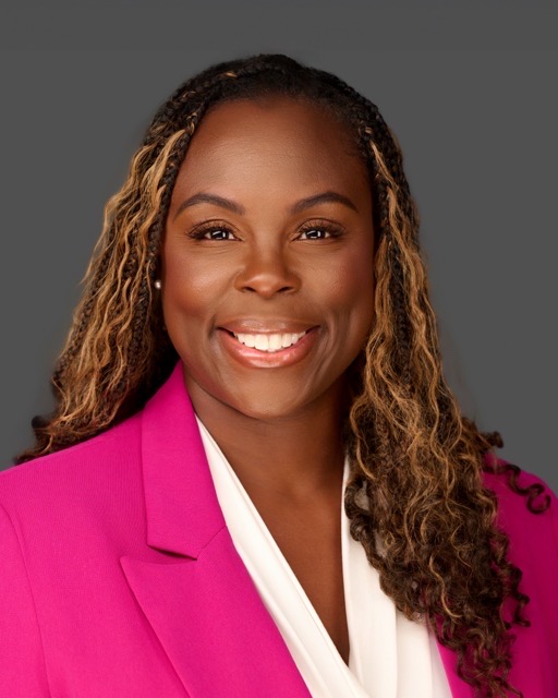 Clean, natural, corporate headshot photo with makeup on deep toned woman smiling in hot pink blazer over white dress top.